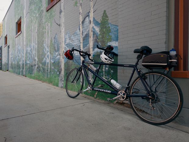 A tandem bicycle parked beside a mountain mural in Leadville