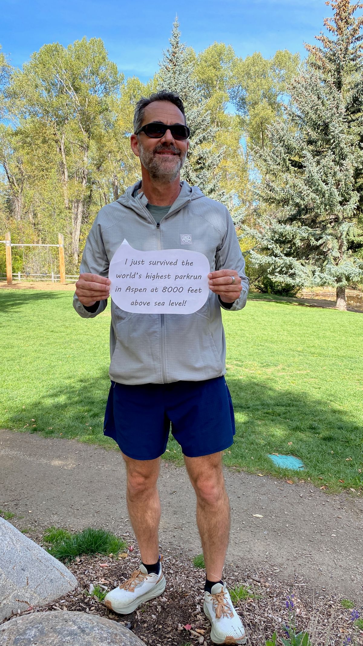 A runner holding a sign celebrating completing the high-altitude Aspen parkrun