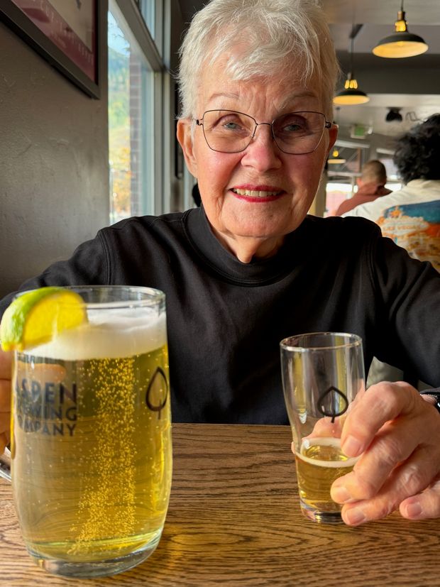 A smiling woman raising a small glass across the dinner table