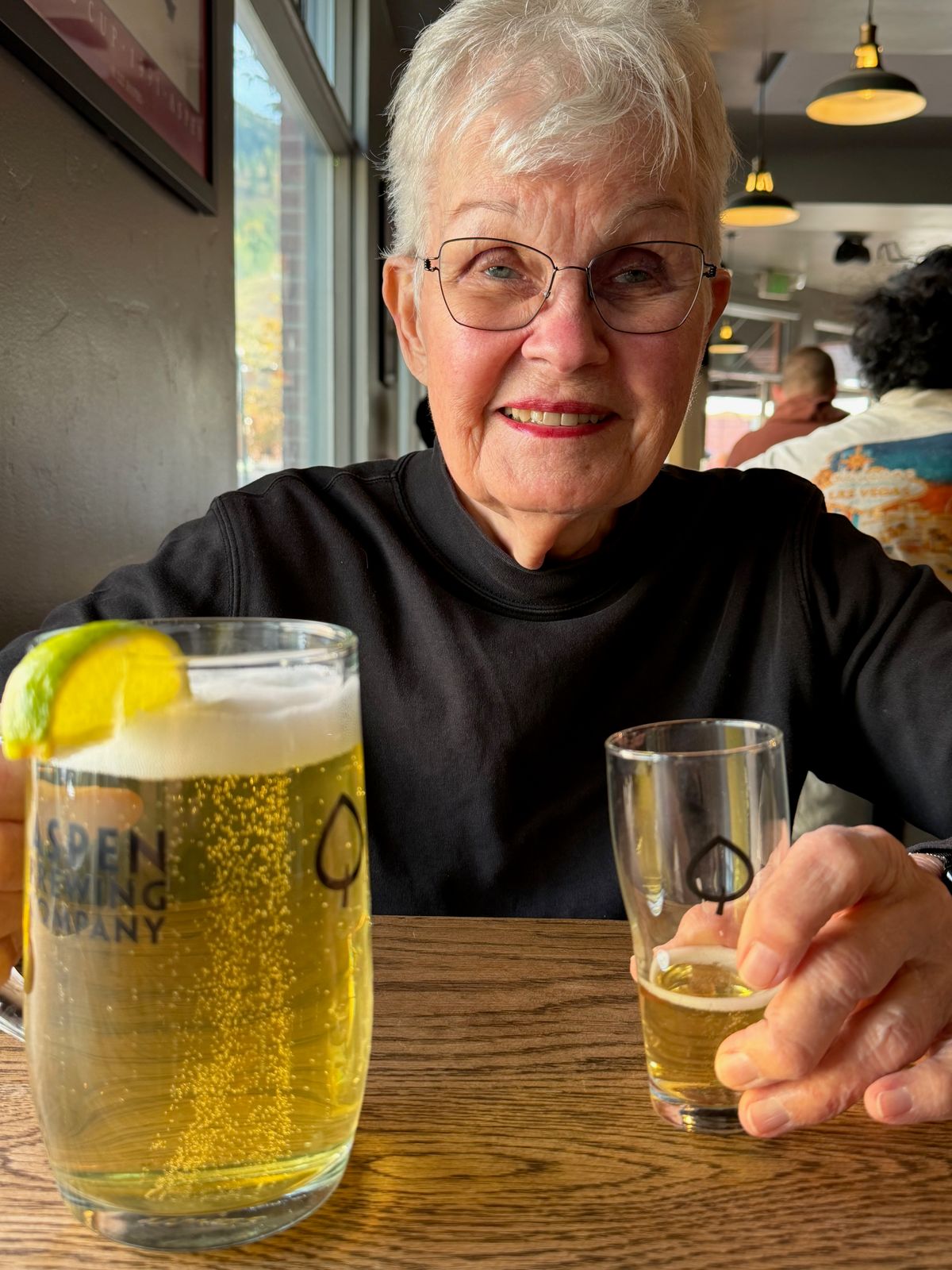 A smiling woman raising a small glass across the dinner table